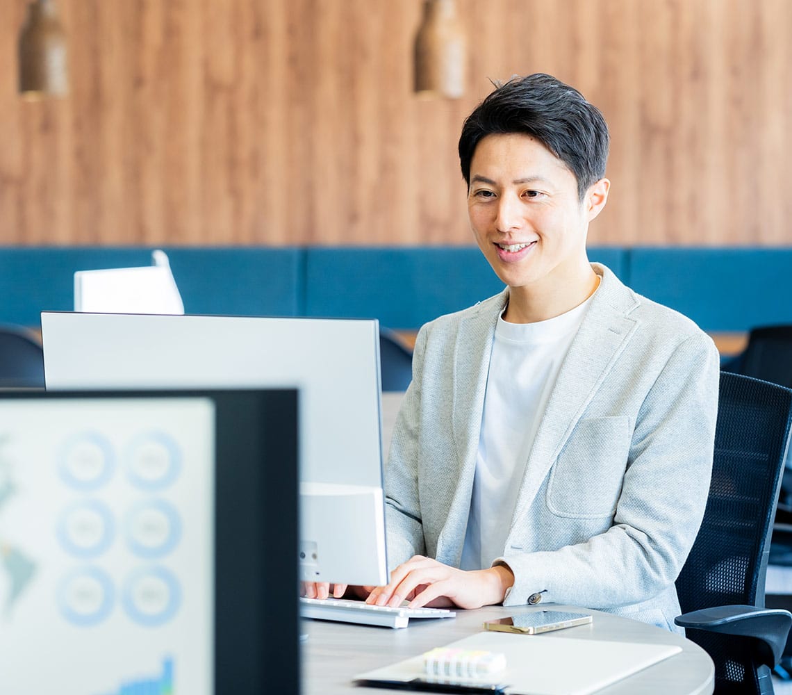 A man in a blazer working on his computer.